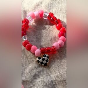 Pink and red beaded bracelet  with checkered black and white heart